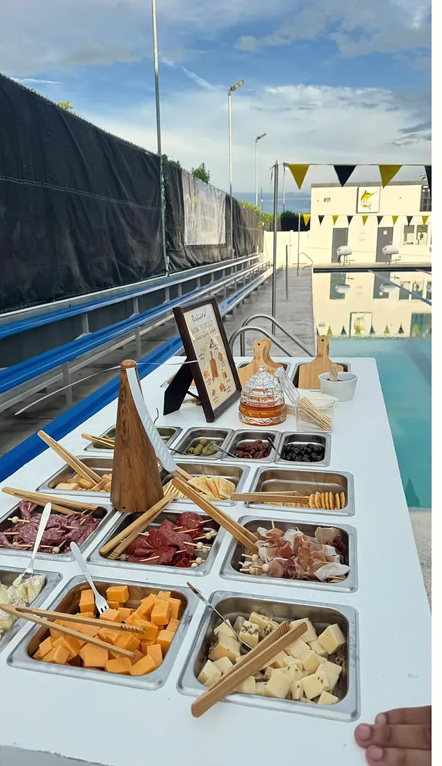 The charcuterie cart by a pool, its pans filled with cheeses, cured meats and fruit
