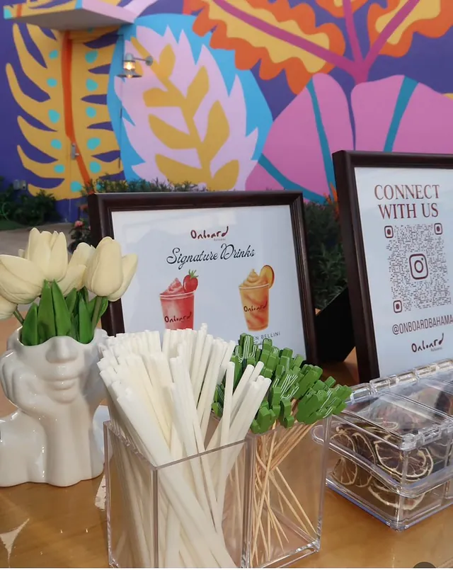A signature drinks menu, straws and white tulips in front of a bright mural